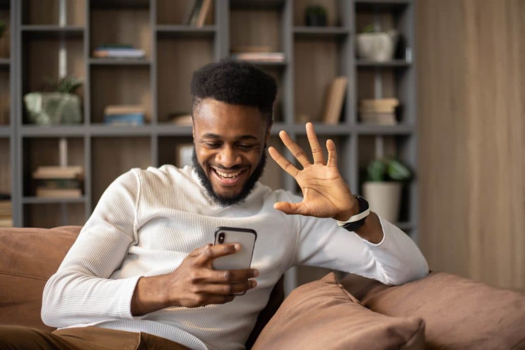 A young man talking on his phone while sitting on a couch