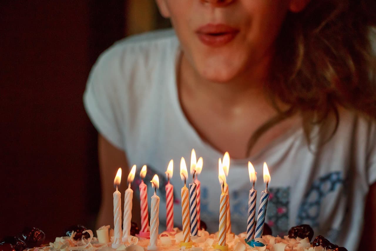 A photo of a young woman blowing out birthday candles.