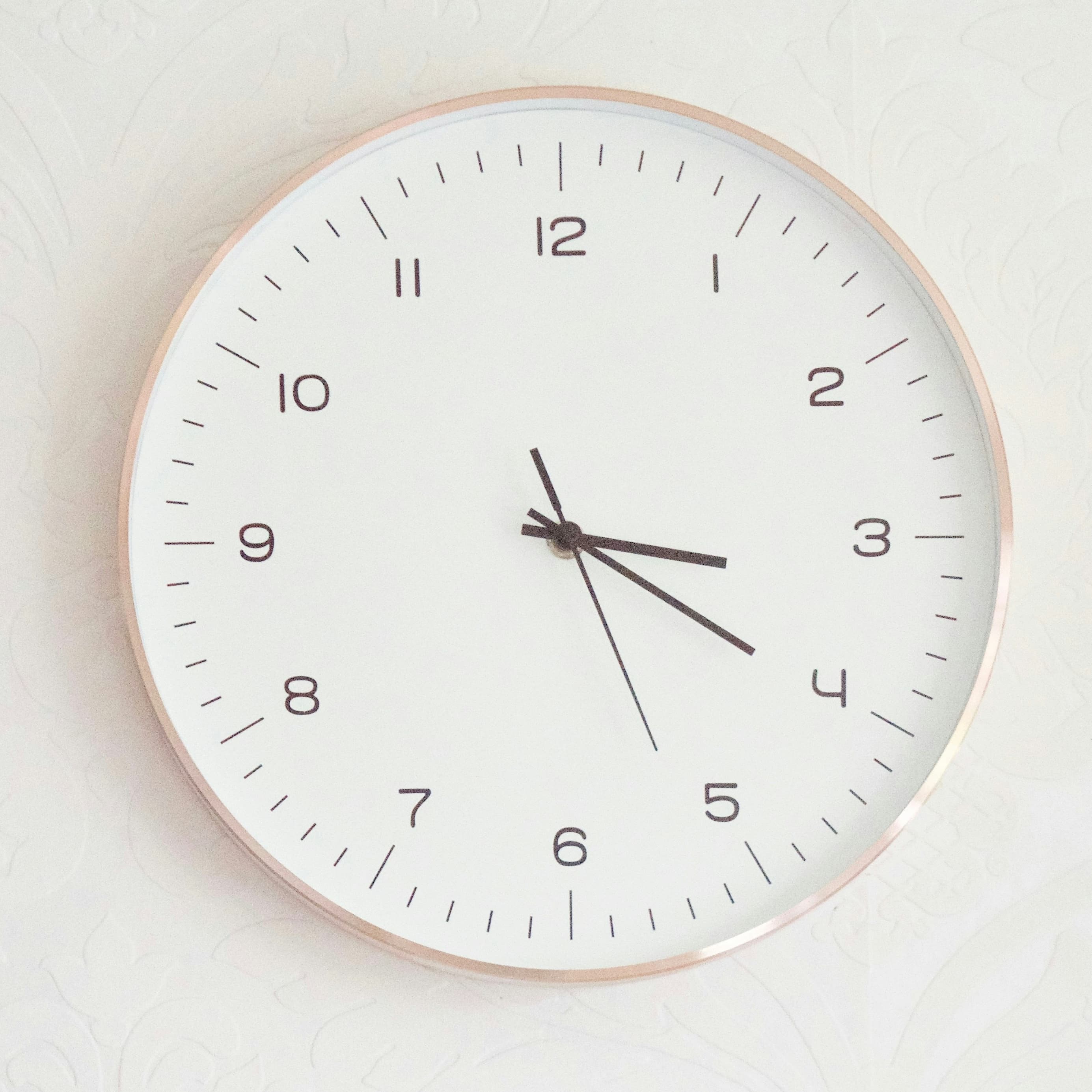 A photo of a modern white analog clock reading 3:20.