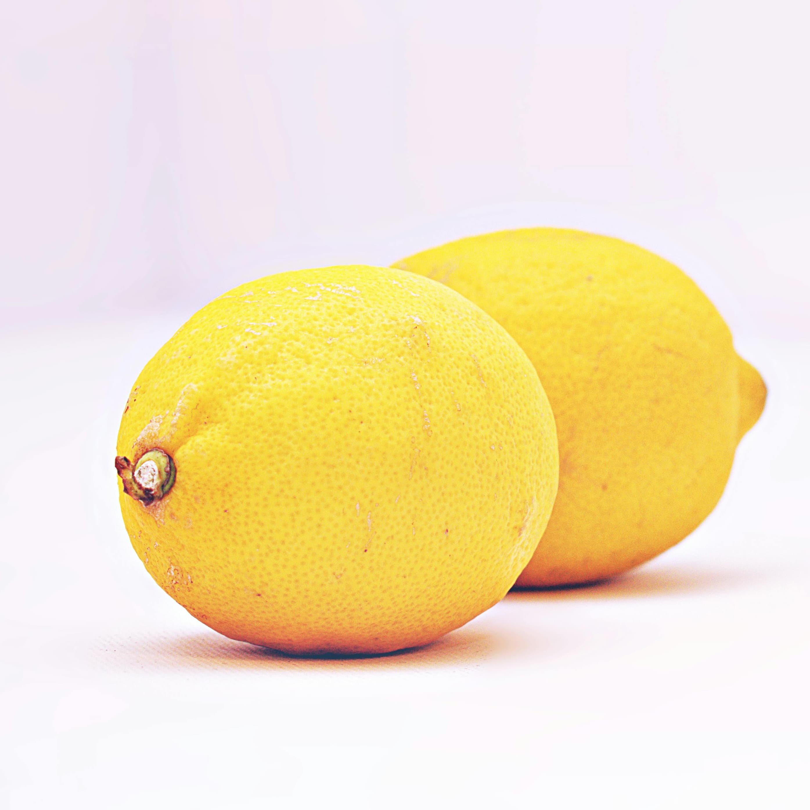 A photograph of two lemons on a white background.