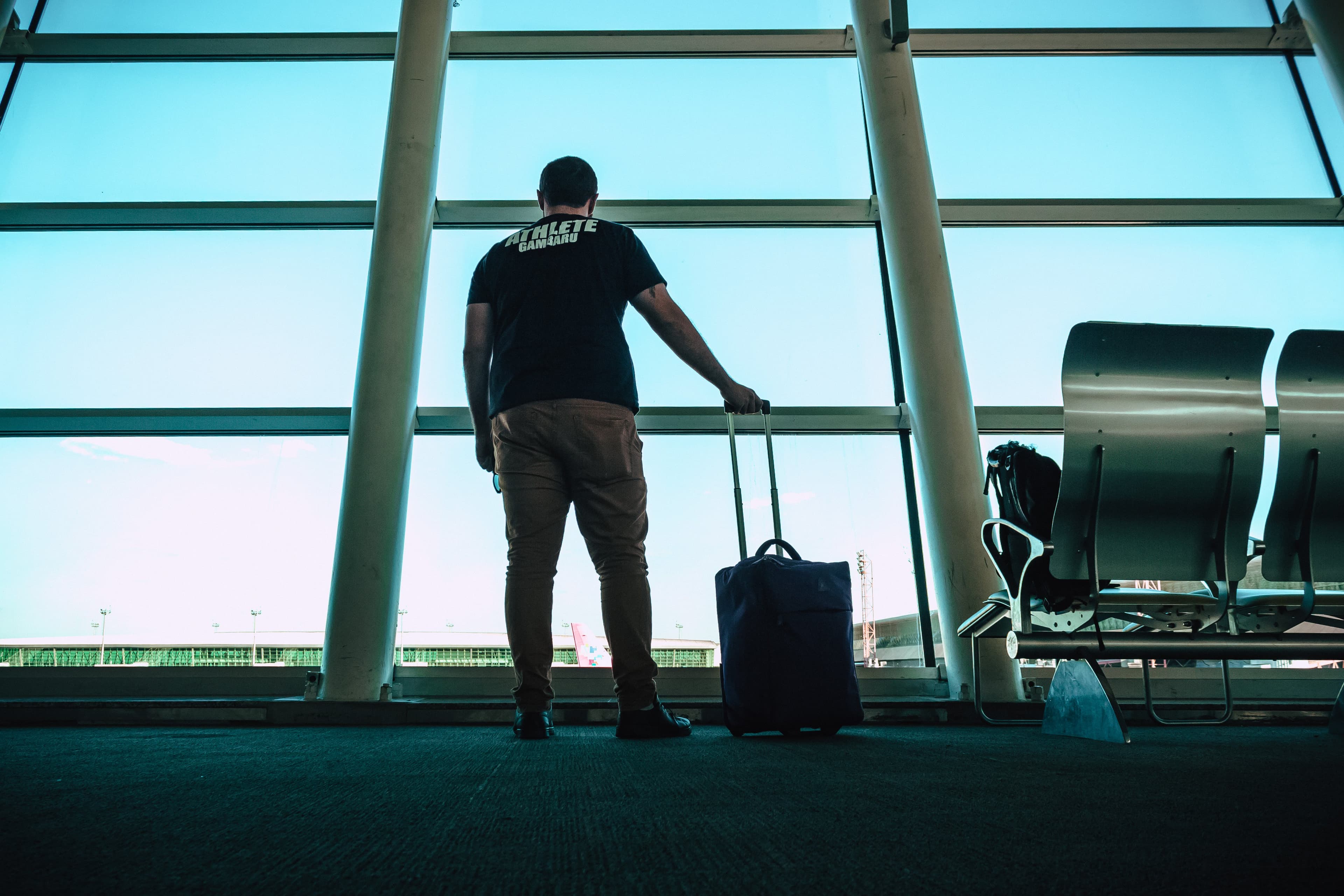 A man looking out a large window at an airport
