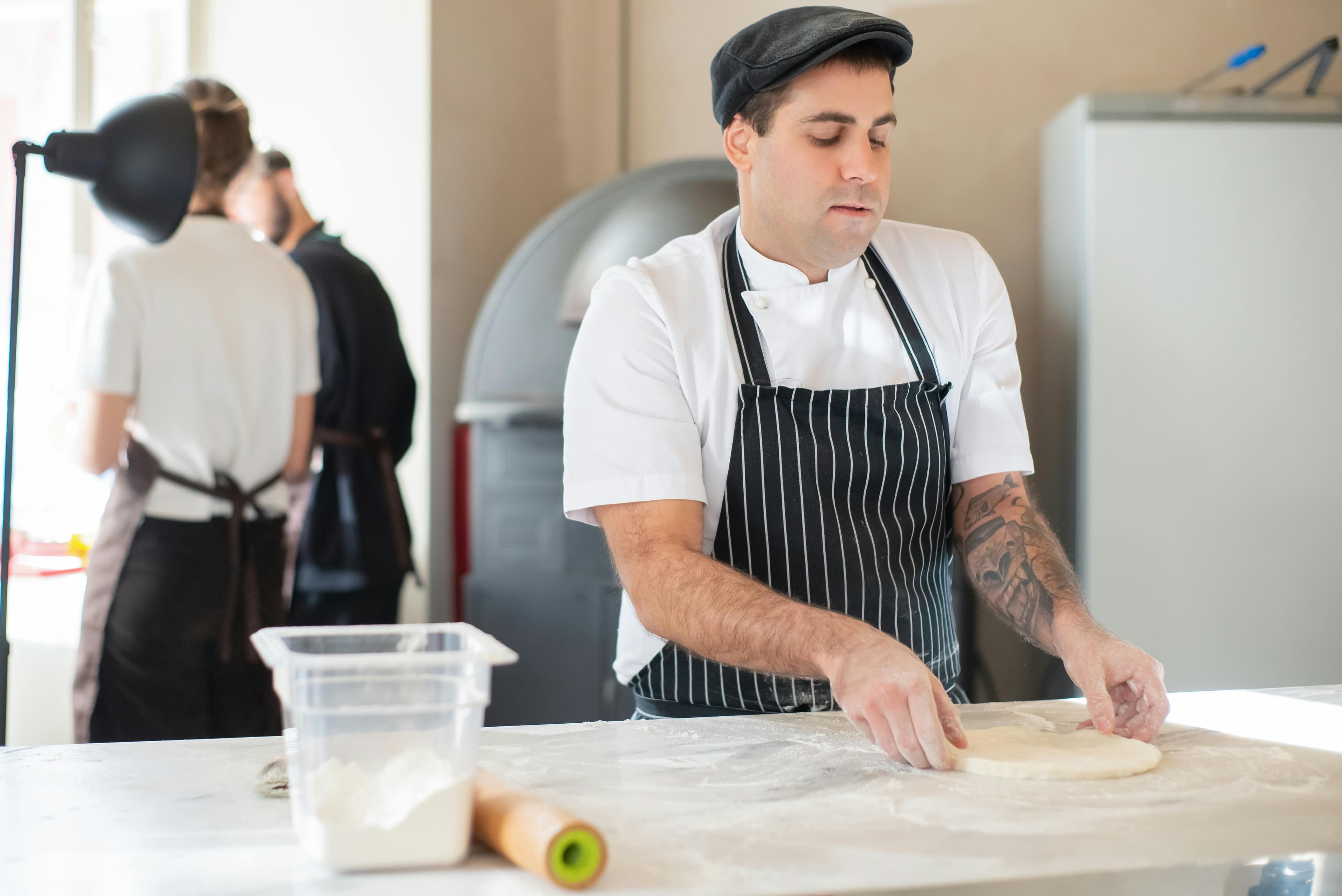 A man making a pizza in an industrial kitchen.