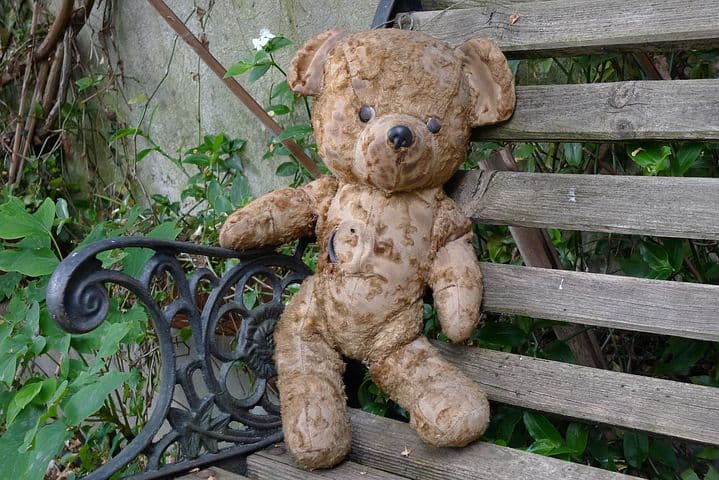 an old teddy bear on a bench