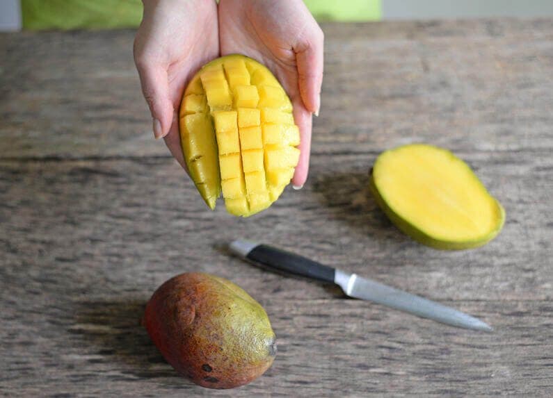 A person showing how a mango can be cut in pieces