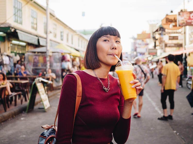 A woman in the street drinking a mango smoothie
