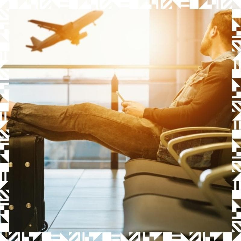 A person sitting  in an airport waiting area resting with his feet up on a luggage