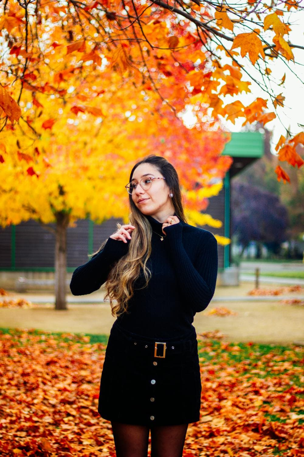 a young woman with long hair wearing a skirt and standing near a tree