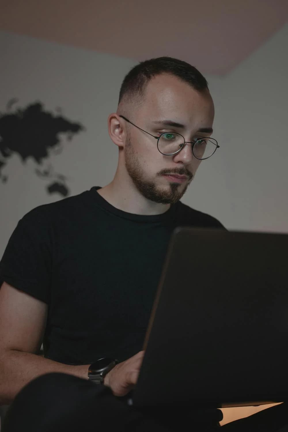 a man with a beard and moustache working on his laptop