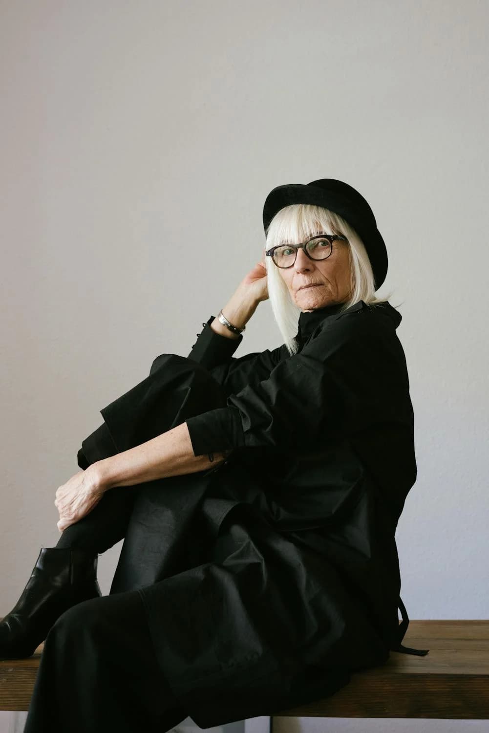 A sitting woman with white hair and a black hat
