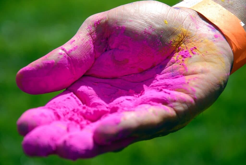 A hand holding a bright pink pigment