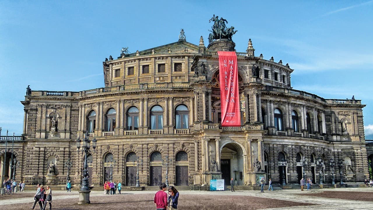A photo of the Semperoper Opera House in Dresden, a round classical building in front of a brick plaza.