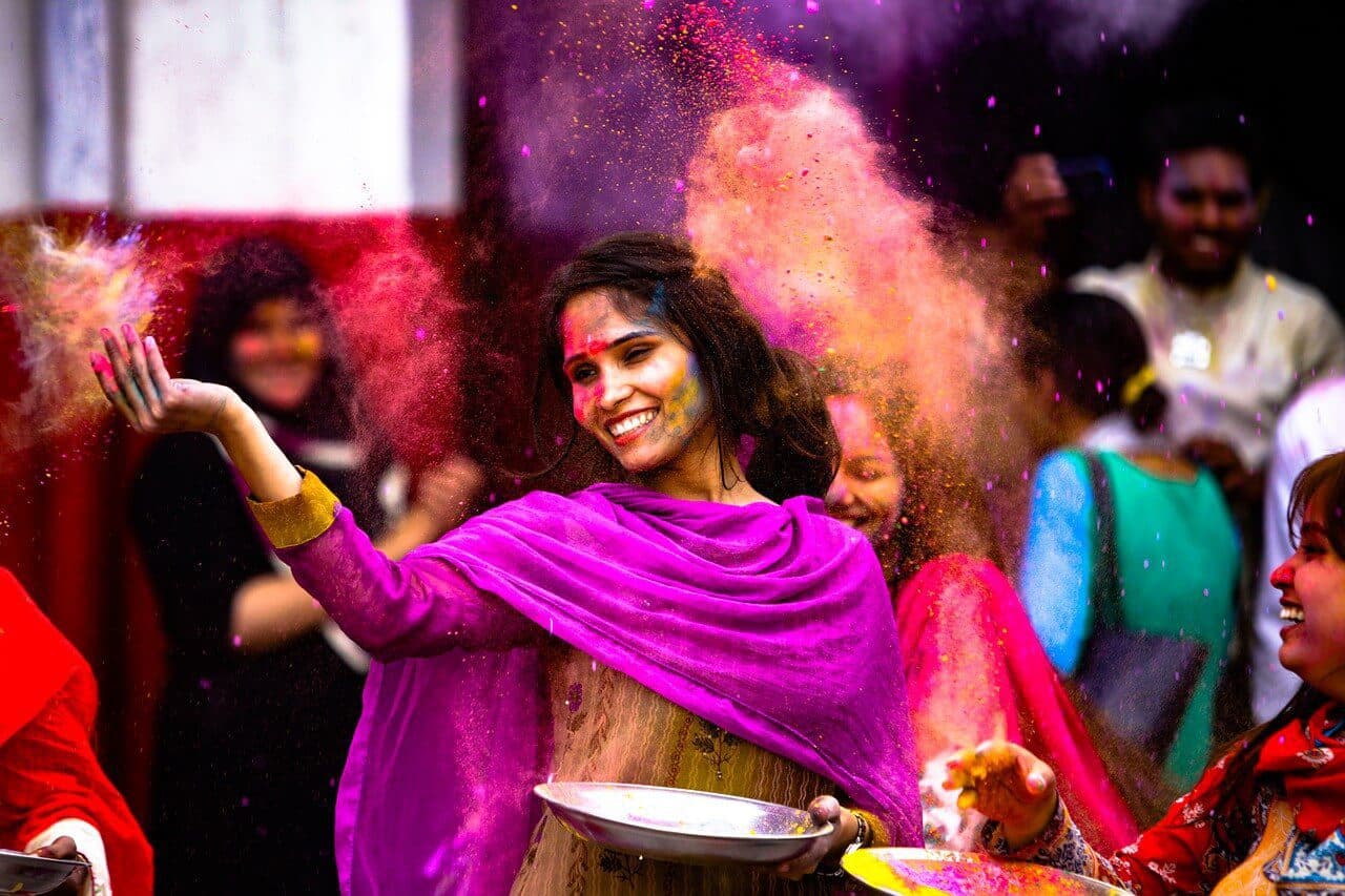 A young woman wearing traditional clothings throwing colorful powder for the Holi celebrations