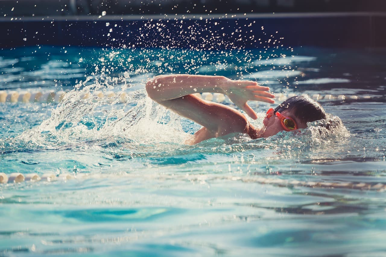 A photo of a boy swimming laps in a pool.
