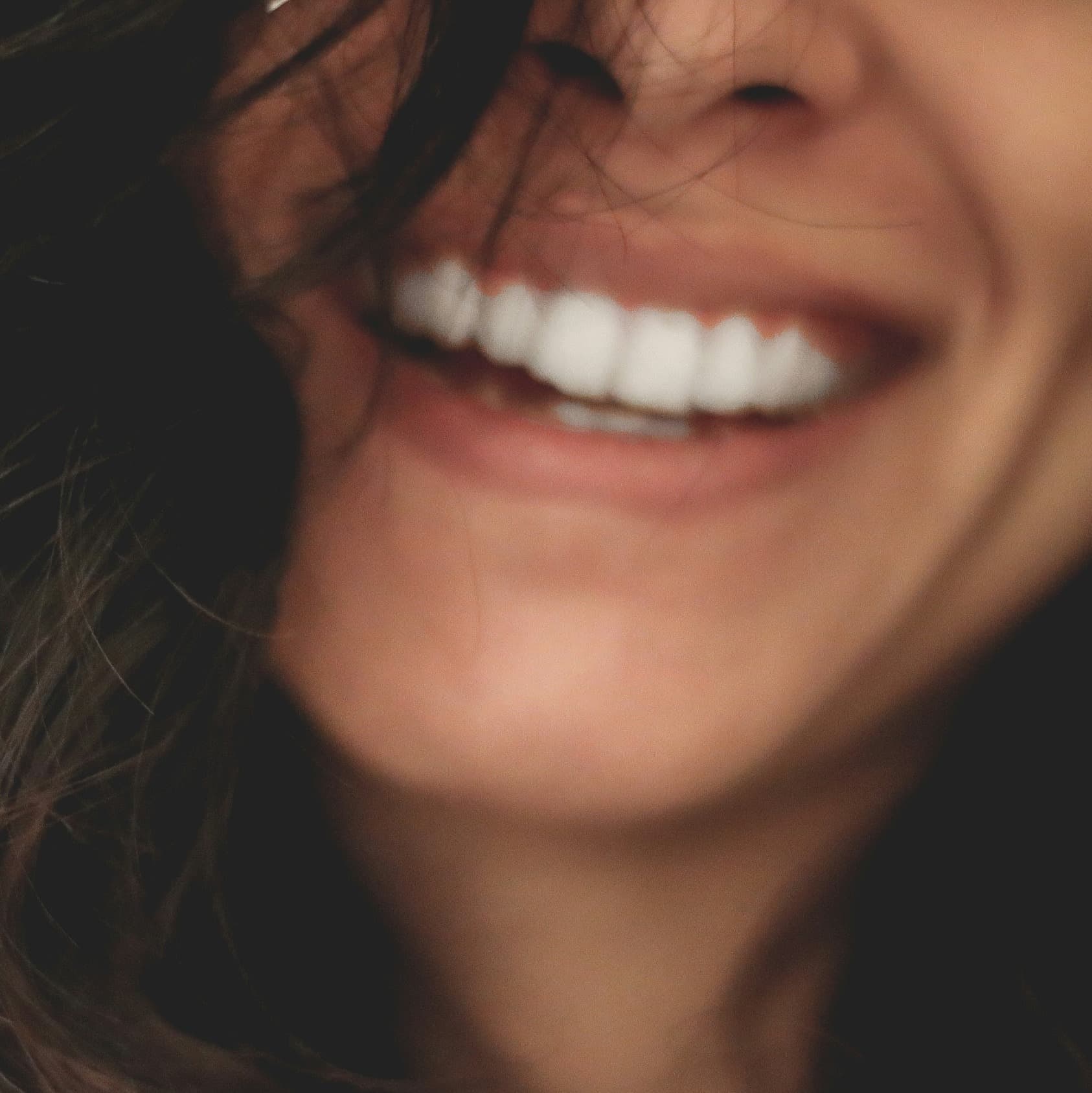 A photograph shows the lower part of a woman's face as she smiles.