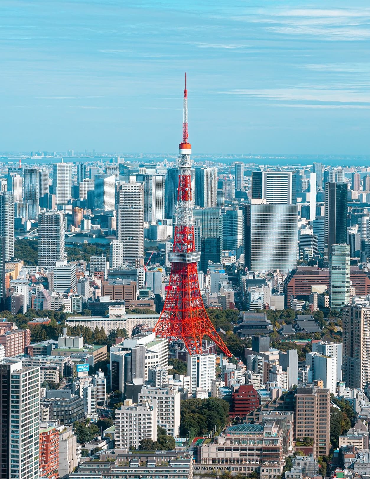 Aerial view of Tokyo skyline featuring Tokyo Tower on the left, with its distinctive red and white pattern.
