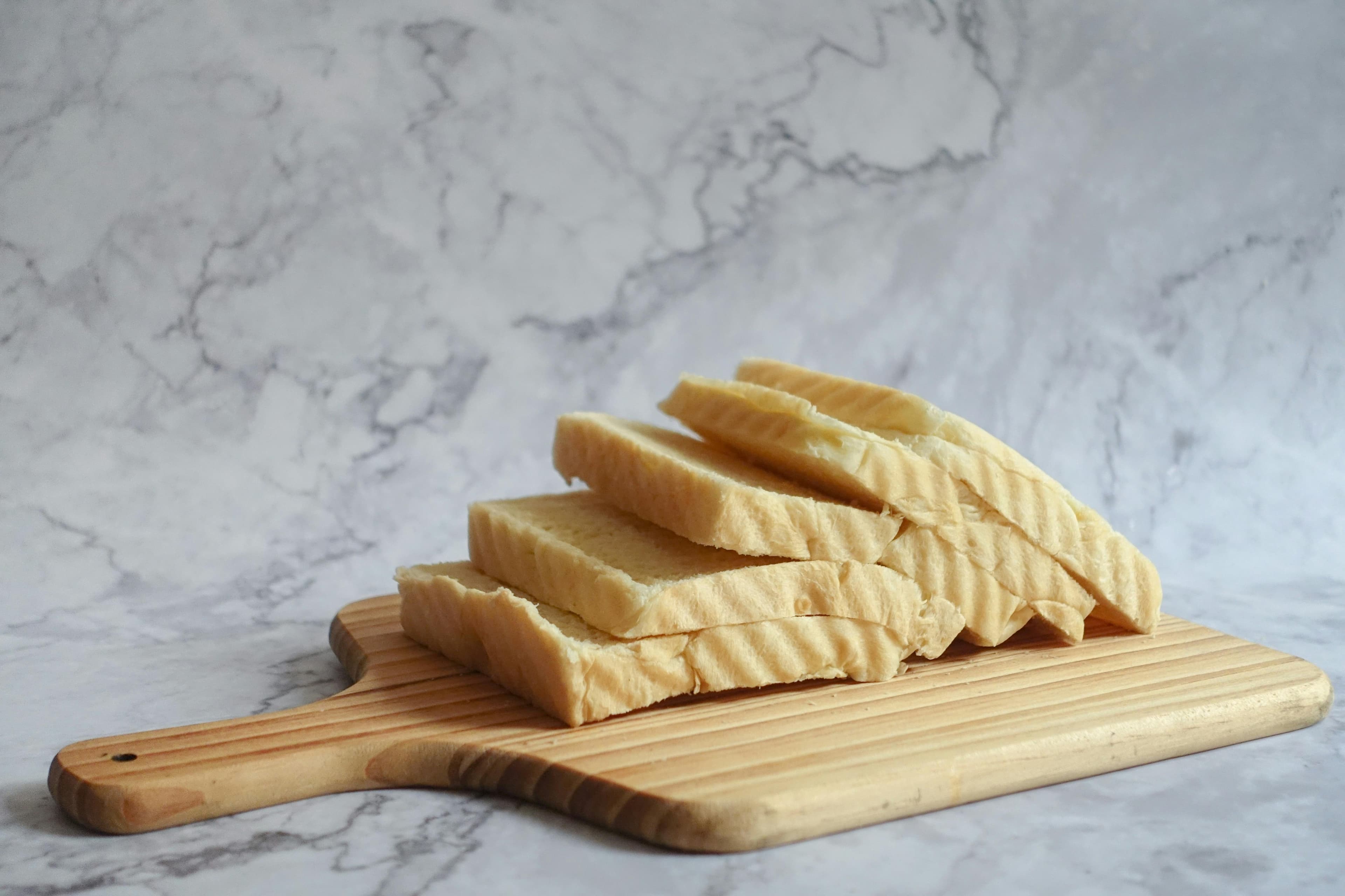 A photo shows a cutting board with 5 slices of bread against a white marble background.