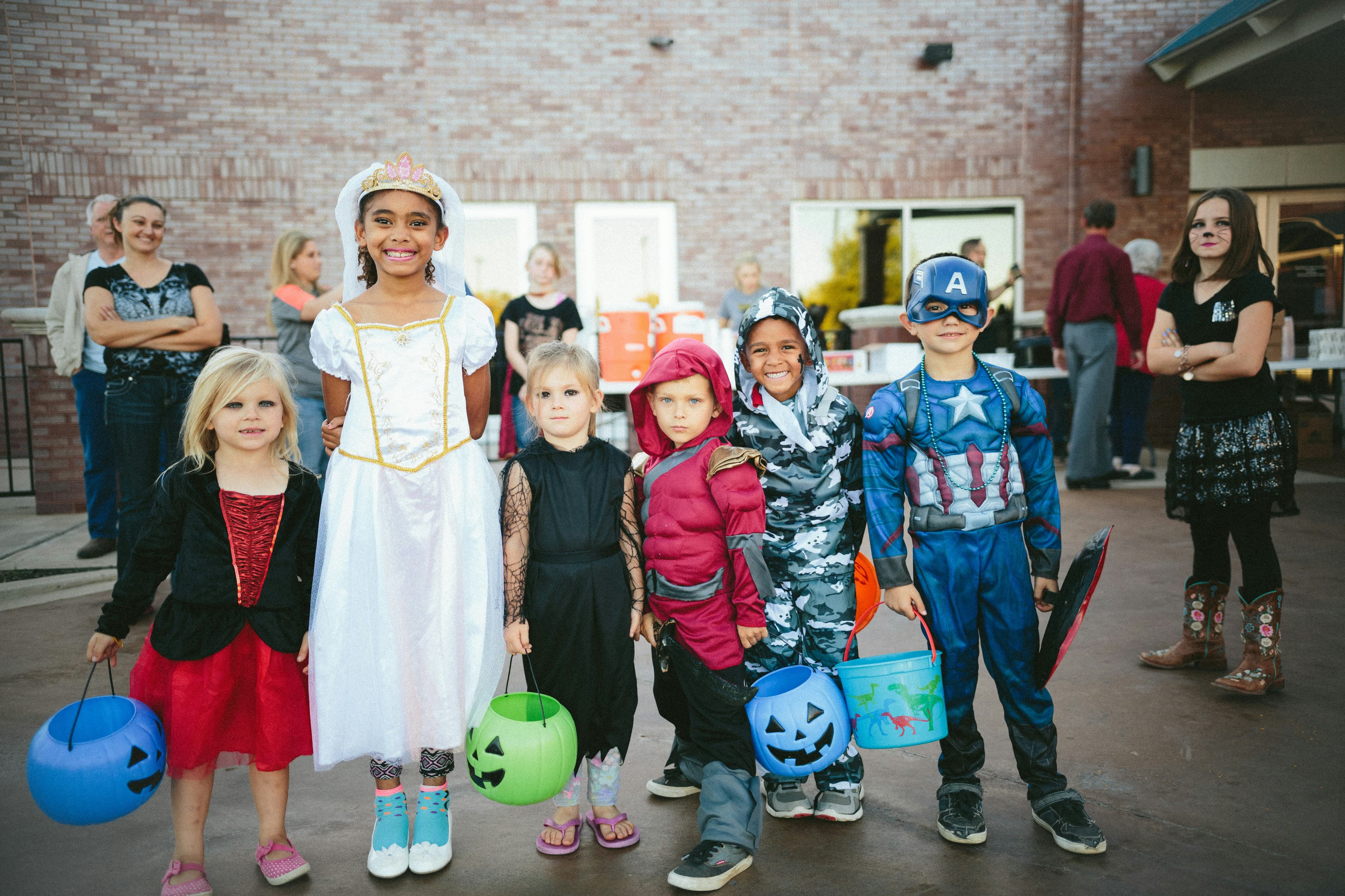 A photo of a group of six children in various halloween costumes holding candy buckets.
