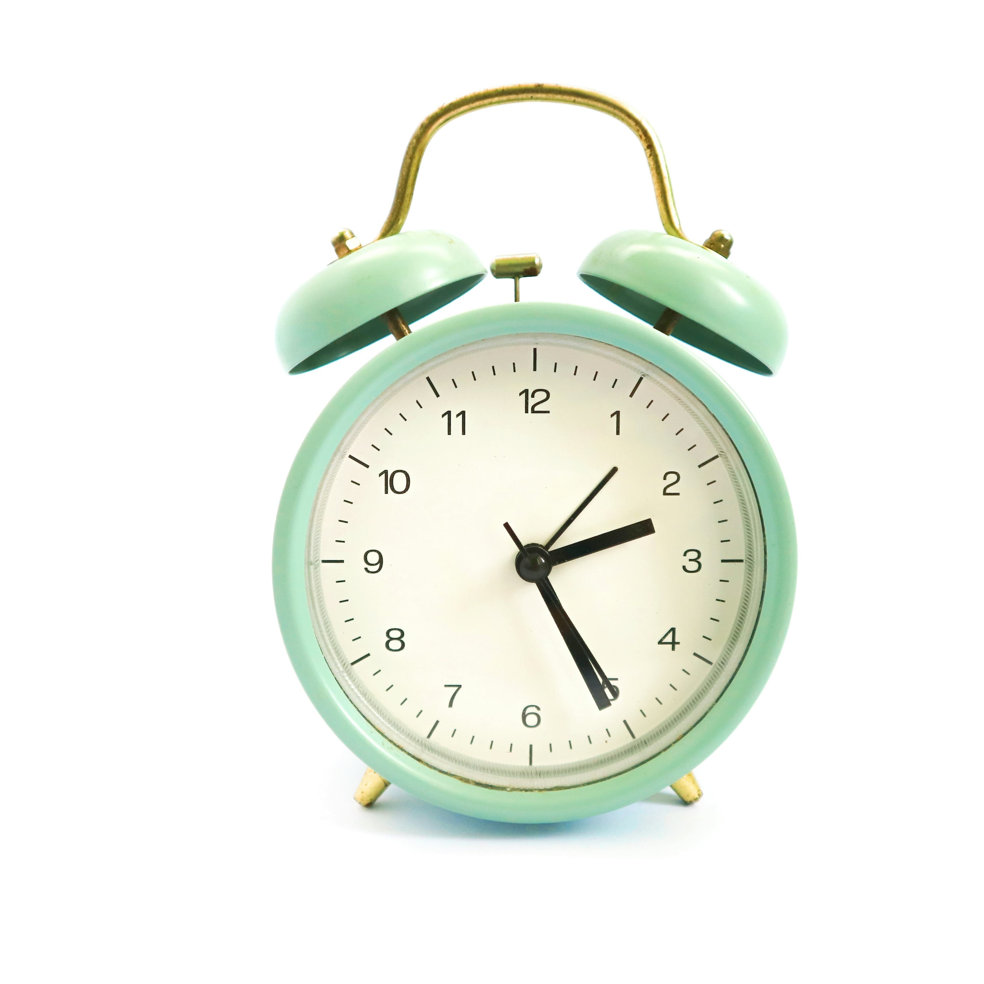 A photo of a mint green analog alarm clock.