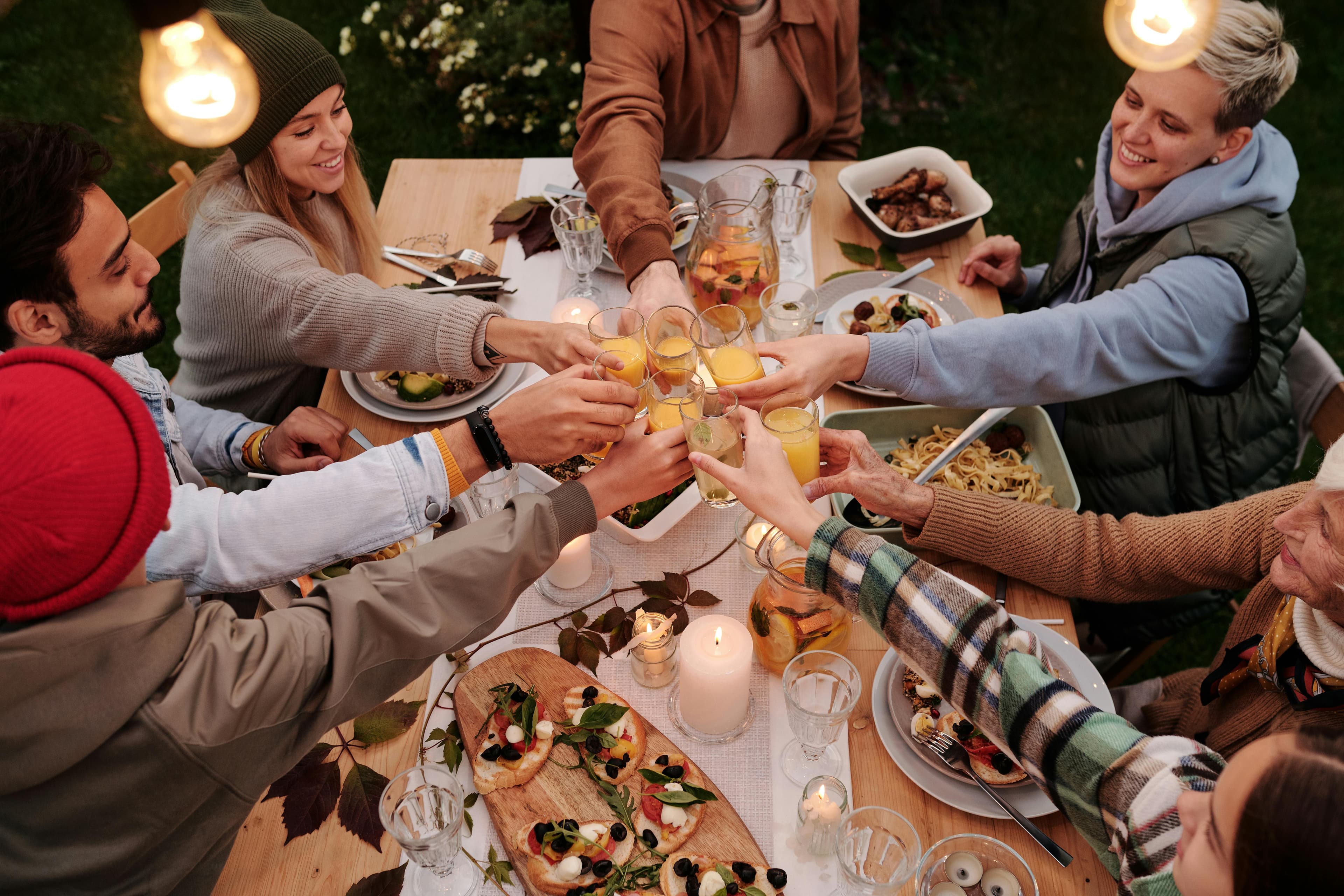 A group of people around a table are performing a toast over a table full of food.