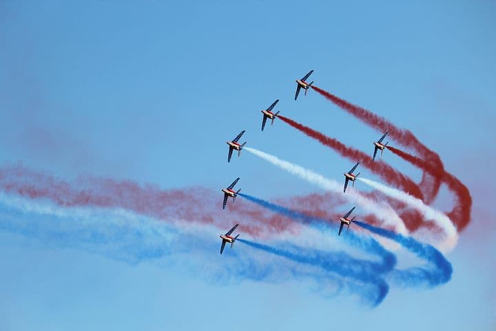 Eight airplanes in formation, releasing red, white, and blue trails.