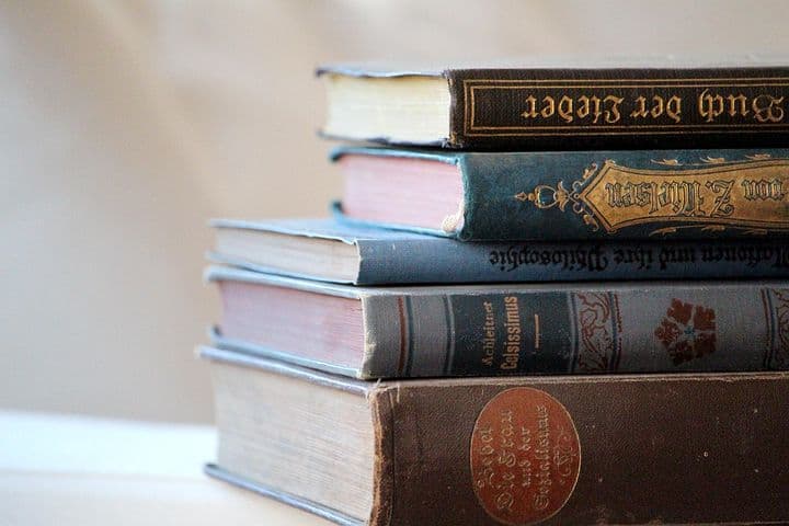 Five antique books in a stack.