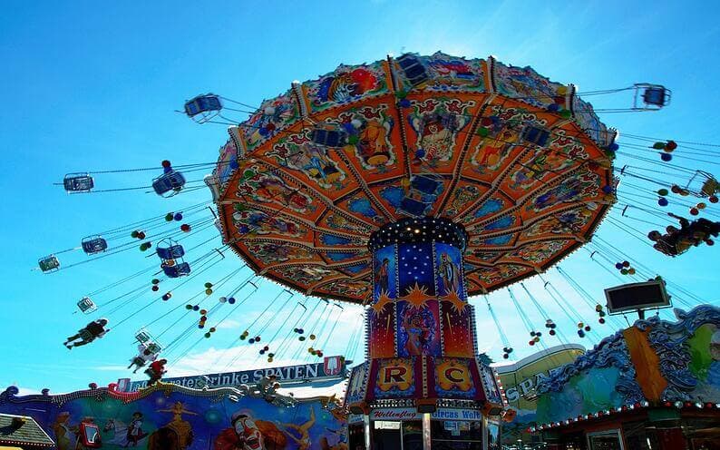 An orange carnival chair swing ride in mid-operation.