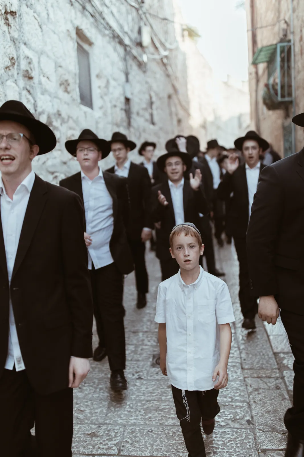 A crowd of Hasidic men in black hats and coats, gathered closely together